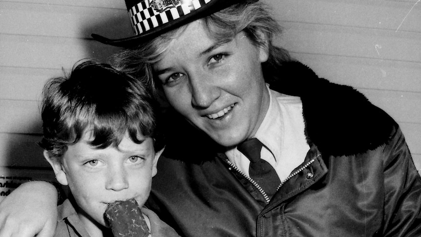 A black and white photo of ya oung Katarina Carroll, in uniform, alongside a child eating ice cream.
