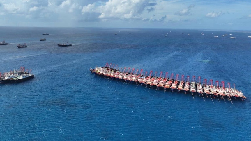 An aerial photo of a series of ships lashed side to side in a line. 