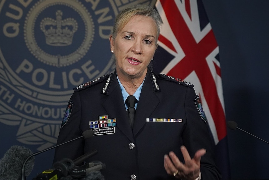 Katarina Carroll standing in front of a QPS logo at a press conference.