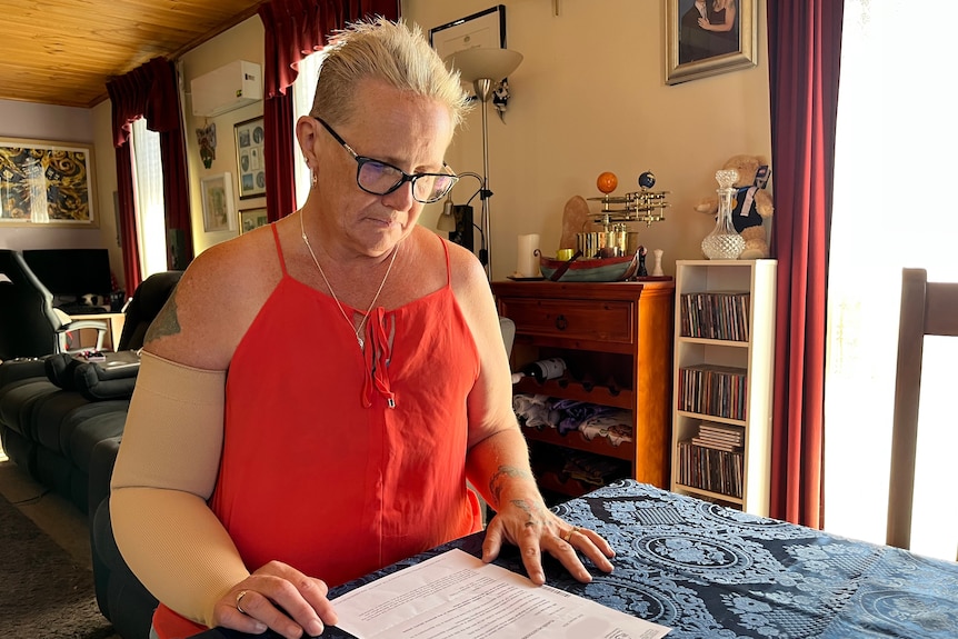 Sue Kole sits at a dining table with a printed letter from the Tasmania Health Service in front of her